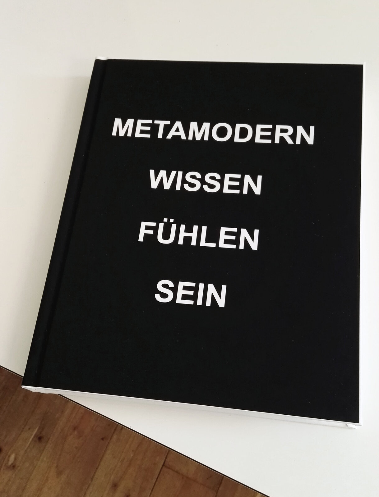 Black hardcover book with white lettering: METAMODERN WISSEN FÜHLEN SEIN