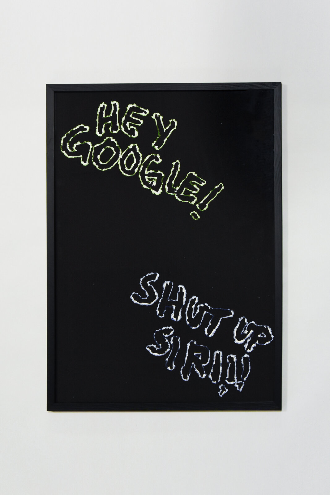 Neon-outline lettering on black reading 'HEY GOOGLE!' in green and 'SHUT UP SIRI!!!' in blue, framed